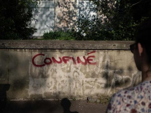 Une femme regarde un graffiti avec l'inscription "confiné" sur un mur durant le premier confinement dû à l'épidémie de Covid-19 Nantes, France - 2020