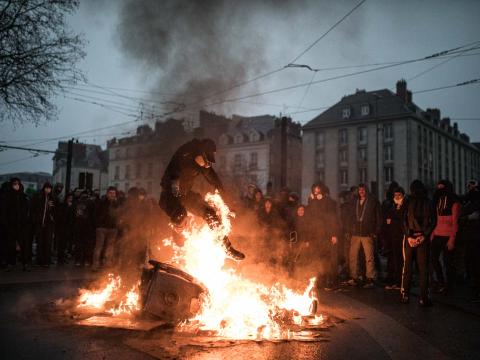 Un manifestant saute par dessus une poubelle enflammée durant un rassemblement des "gilets jaunes" Nantes, France - 2019