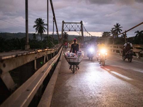 Un homme transporte des biens de consommation par brouette sur le pont désormais interdit à la circulation des camions. Jeremie, Haïti. Septembre 2021
