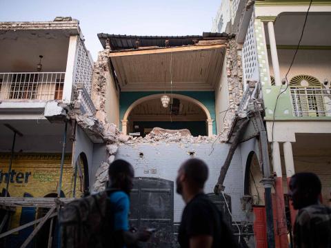 Trois hommes observent la façade détruite d’un immeuble d’habitation dans le centre historique. Jeremie, Haïti. Septembre 2021