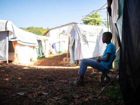 Un adolescent est assis devant la tente qui lui sert de logement à la suite du séisme. Région de Pestel, Haïti. Septembre 2021