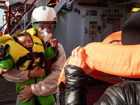 Blandine, sage-femme de l’équipage, prend en charge un bébé qui vient d’être secouru pendant que la mère de celui-ci ôte son gilet de sauvetage. Méditerranée Centrale. Mars 2021