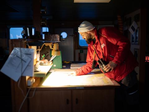 Anthony, membre de l'équipe de recherche et sauvetage et photographe observe une carte au début de son tour de veille. Méditerranée Centrale. Mars 2021