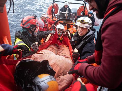 Des membres de l'équipage hissent un mannequin allongé sur un brancard depuis un semi-rigide jusque sur le pont de l'Ocean Viking lors d'un entraînement.