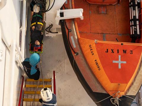 Une membre de l'équipage allongée sur un brancard est hissée sur des escaliers par des membres de l'équipe de recherche et sauvetage durant un exercice de simulation d'une évacuation sanitaire par hélicoptère.
