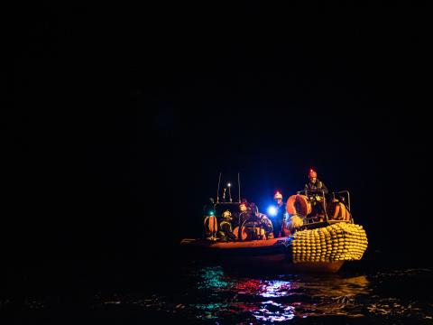 Des membres de l'équipe de recherche et de sauvetage sur un semi-rigide au milieu de la mer totalement plongée dans l'obscurité lors d'un exercice nocturne.