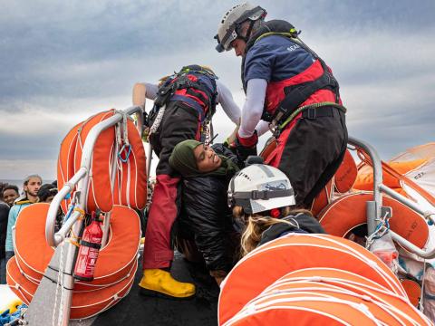 Une rescapée quitte l'embarcation surchargé sur laquelle il vient d'être secouru. Il est aidé par des membres de l'équipe de recherche et de sauvetage à monter à bord du semi-rigide d'intervention.
