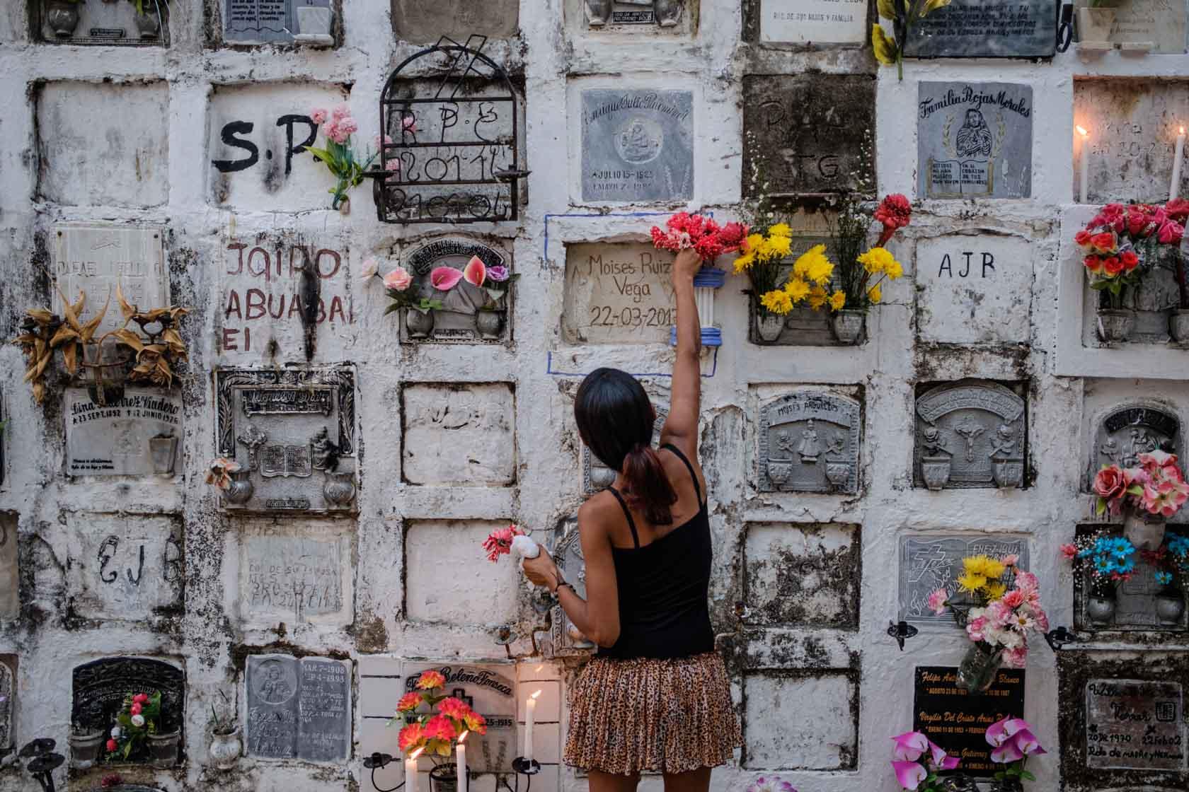 Une jeune femme fleurit une tombe pendant la fête des morts de la semaine sainte Mompox, Colombie - 2018