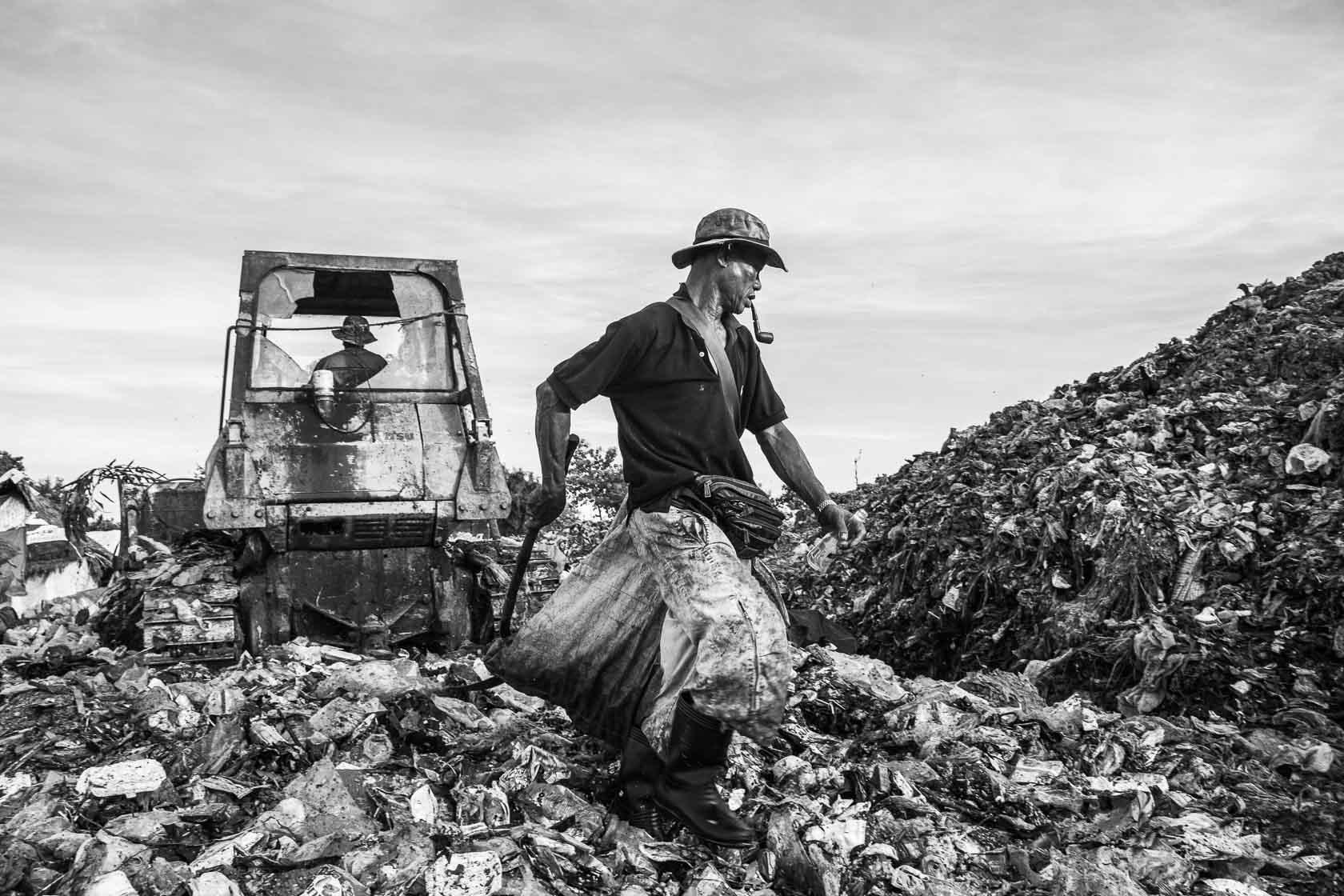 Un migrant birman fouille parmi des déchets dans la décharge ou il habite avec sa famille. Il gagne l''équivalent de 50€ par mois en revendant le métal et le verre qu'il trouve au milieu des immondices Mae Sot, Thaïlande - 2014