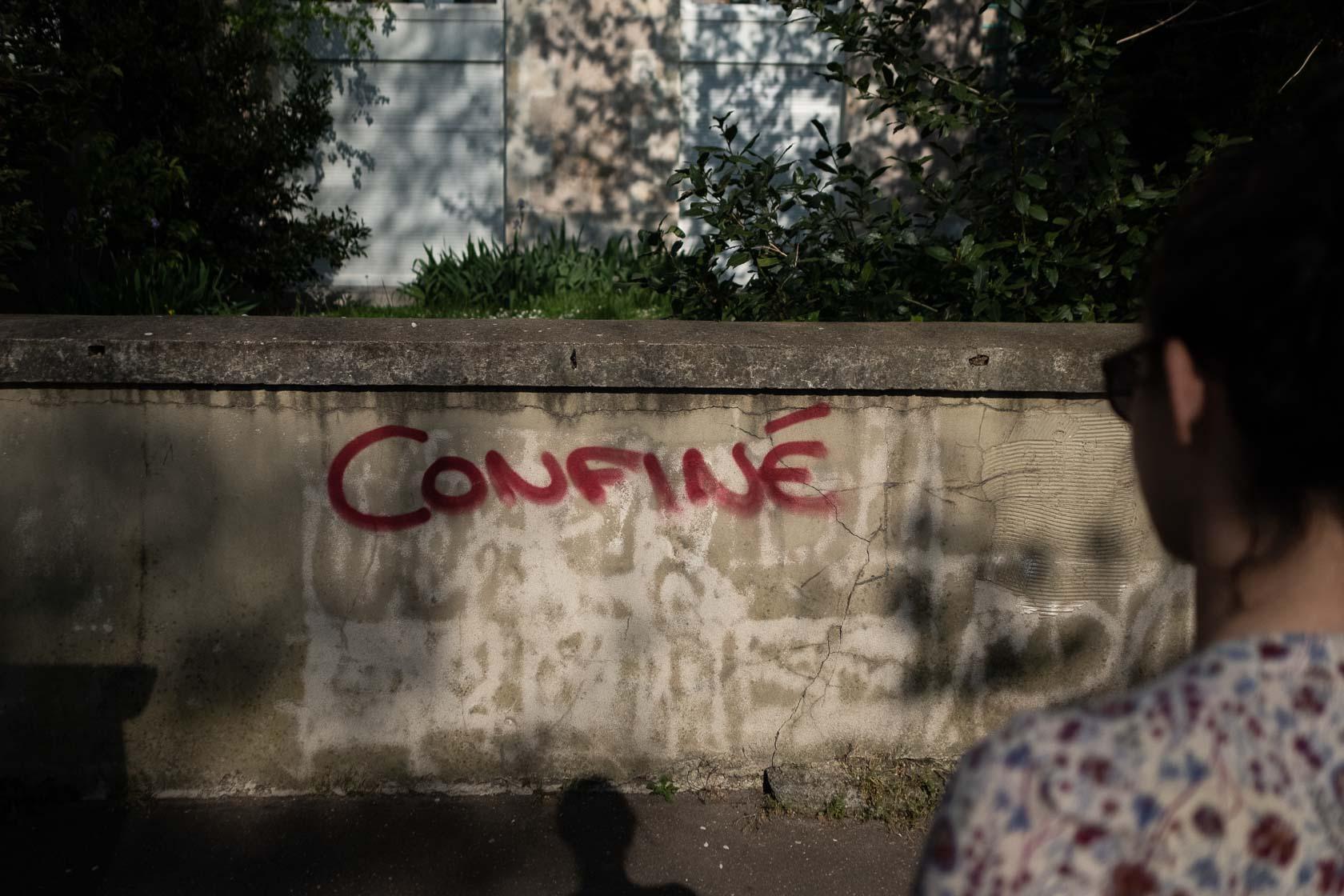 Une femme regarde un graffiti avec l'inscription "confiné" sur un mur durant le premier confinement dû à l'épidémie de Covid-19 Nantes, France - 2020