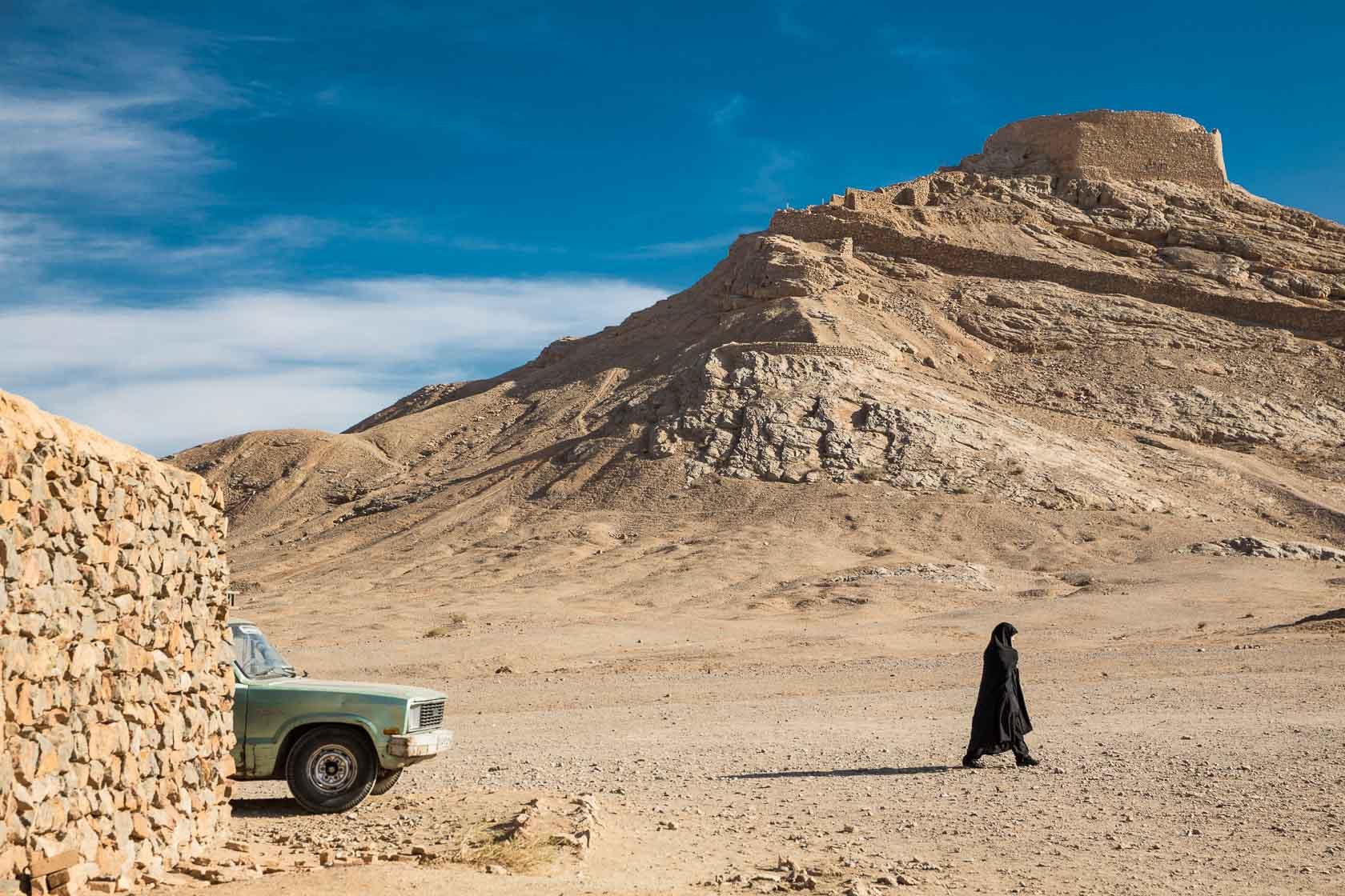 Une femme marche dans une vallée où se situent une "tour de silence" utilisée pour les rites funéraires zoroastriens Iran - 2016