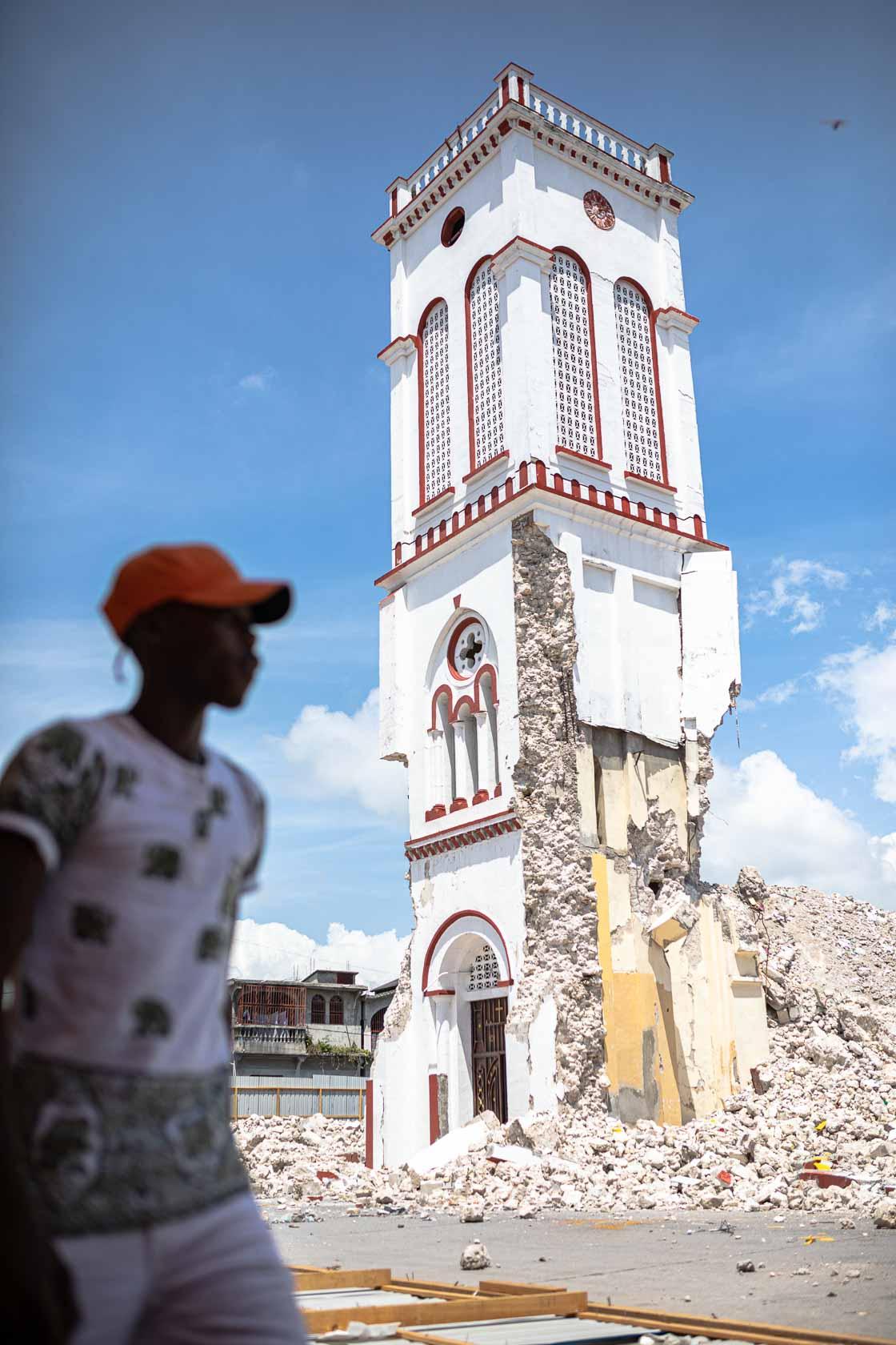 Un jeune homme marche devant l'église principale qui s'est partiellement effondrée durant le séisme. Les Cayes, Haïti - Septembre 2021