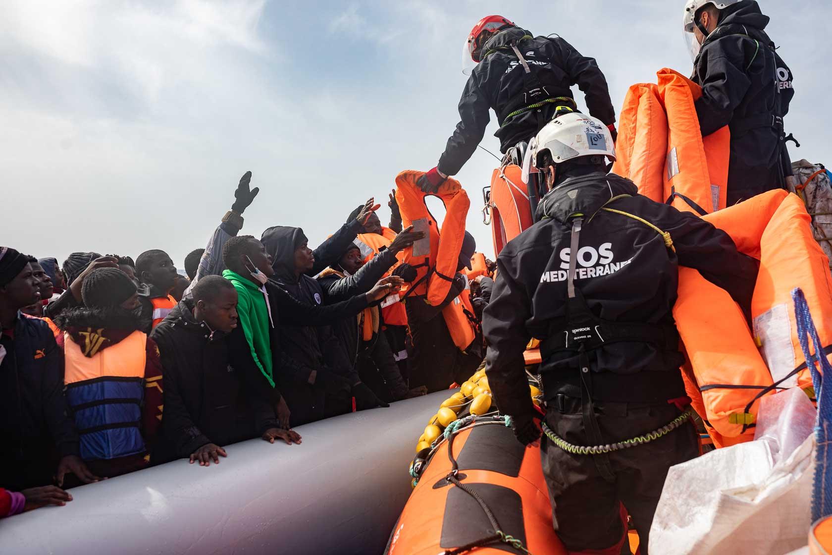 L’équipe du rhib EZ1 distribue des gilets de sauvetage aux occupants d’un bateau pneumatique avant d’entamer leur transfert sur le pont de l’Ocean Viking. Méditerranée Centrale. Mars 2021