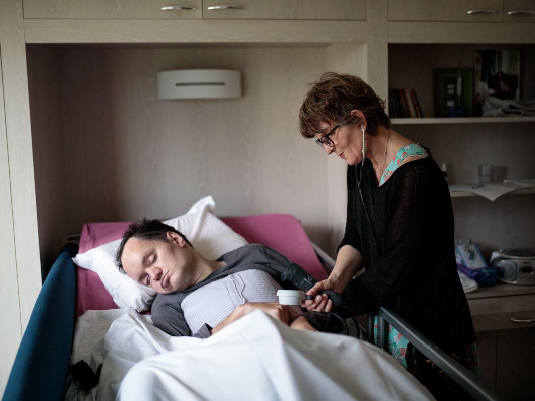 Une infirmière prend la température d'un homme alité dans un établissement Rezé, France - 2018