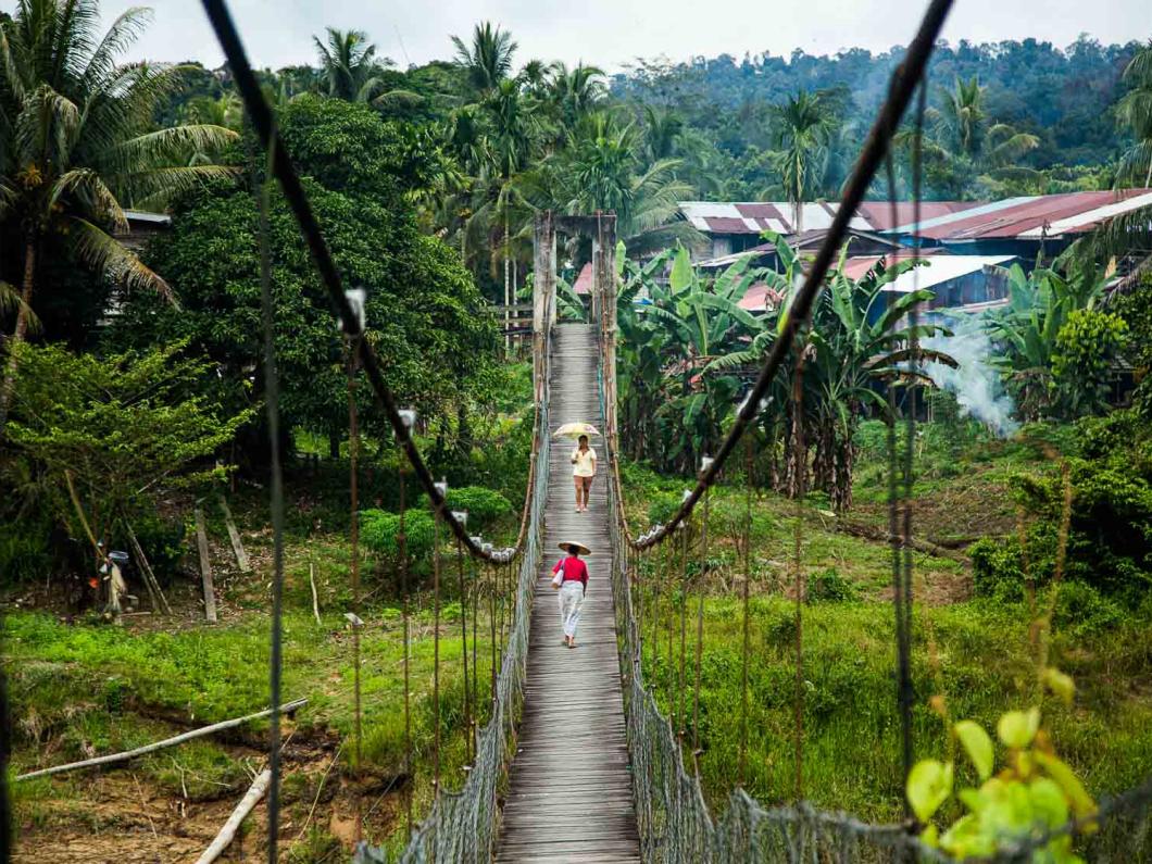 Deux femmes traversent un pont suspendu à l'entrée d'un village ​​​​​​​Punan Bah, Malaisie - 2015